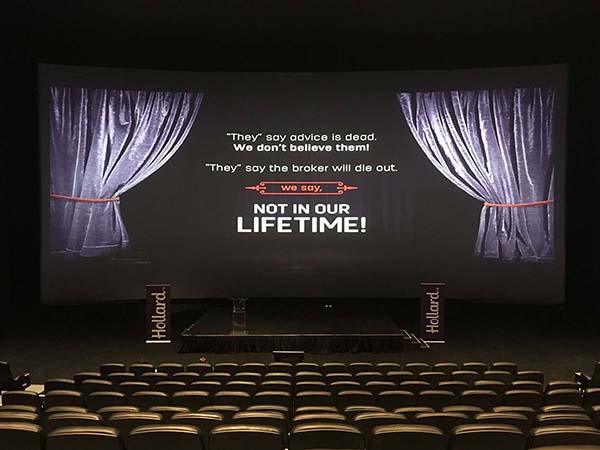 Empty cinema with the following text on the movie screen: "They say advice is dead, we don't believe them! They say the broker will die out, we say, not in our lifetime!