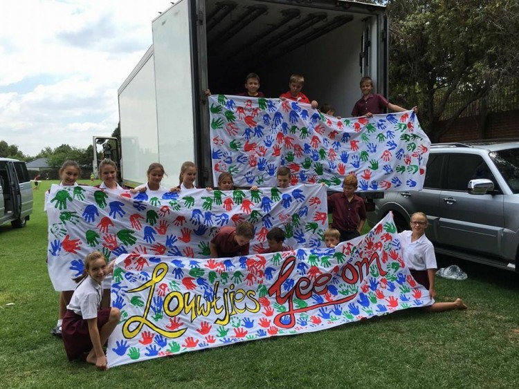 Children from Laerskool Louw Geldenhuys holding a banner that reads 'Louwtjies care'
