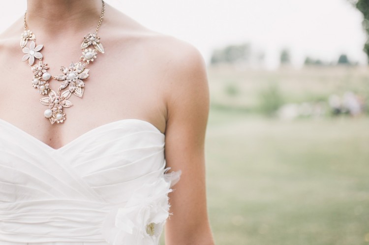 Neck to stomach image of a woman in a wedding dress with a beautiful necklace.