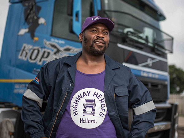 A Highway Heroes Driver wearing HH-branded t-shirt and cap standing proudly in front of his truck.