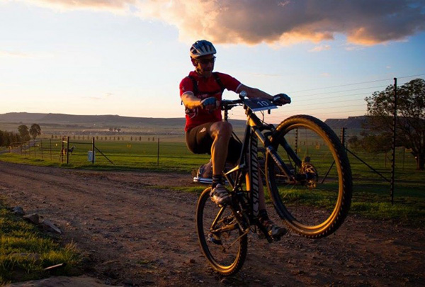 A cyclist competitor "popping a wheelie" in the early-morning countryside
