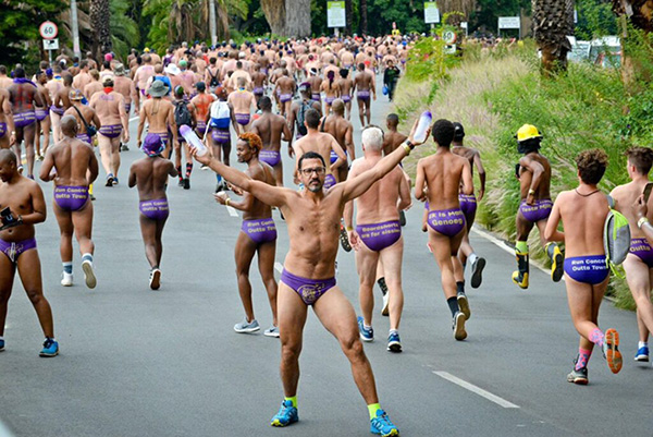 A participant of the Daredevil Run facing oncoming runners while holding water-bottles